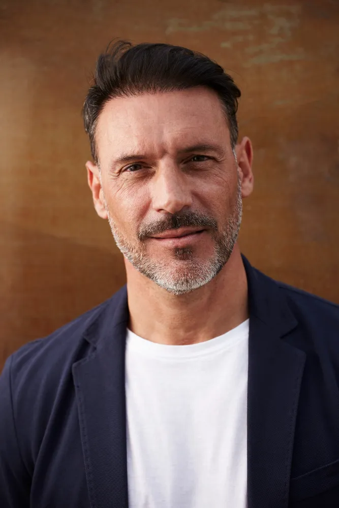 A man with a beard and mustache wearing a blue jacket.